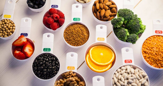 Messbecher mit Obst, Gemüse, Nüssen und Hülsenfrüchten.